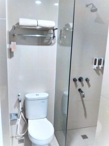 a bathroom with a toilet and a glass shower at Lynn Hotel Serang in Serang