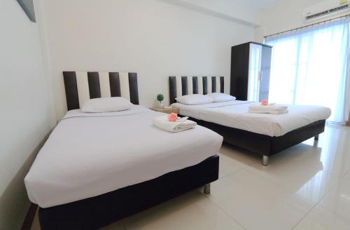 two beds in a room with white sheets and pillows at sk resort in Bangkok