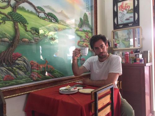 a man sitting at a table with a cup of coffee at Cat Ba Mystery Homestay in Cat Ba