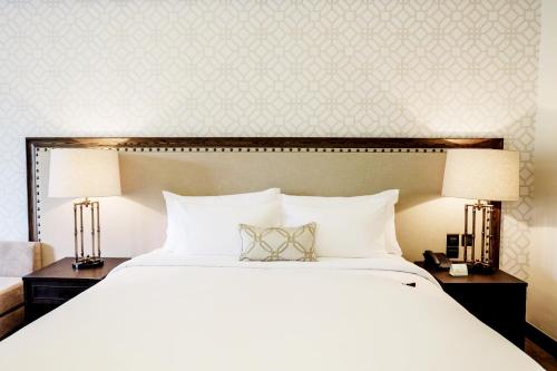 a bedroom with a large white bed with two lamps at Hotel Labaris Khao Yai in Mu Si