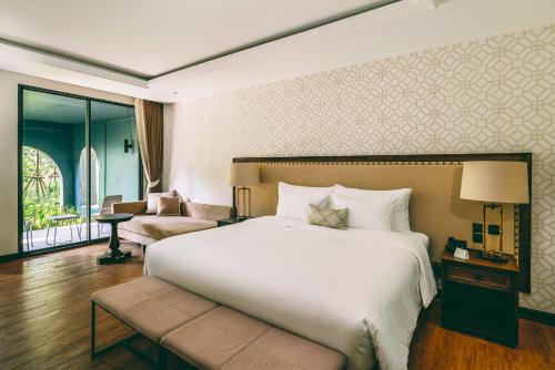 a bedroom with a large bed and a living room at Hotel Labaris Khao Yai in Mu Si