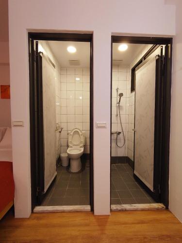 a bathroom with a toilet and a shower with two doors at 高寮貳陸之貳民宿 Gaoliao 26-2 Simple Home Life in Yuli