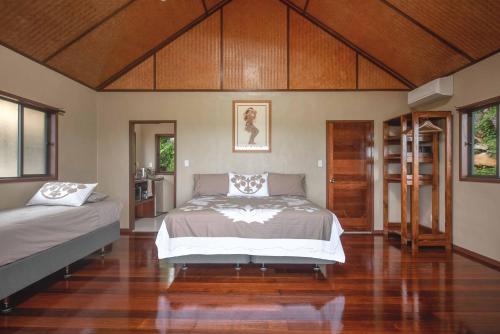 a bedroom with two beds and a wooden floor at Rainbow Villas in Rarotonga