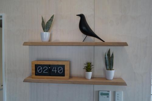 a clock on a shelf with potted plants and a bird at Apartments Hanmer Springs in Hanmer Springs