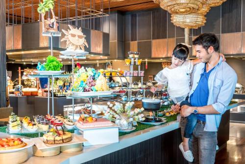 a man and a man holding a child in front of a buffet at Novotel Bangkok Platinum Pratunam in Bangkok