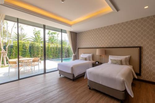 two beds in a hotel room with a balcony at Hotel Labaris Khao Yai in Mu Si