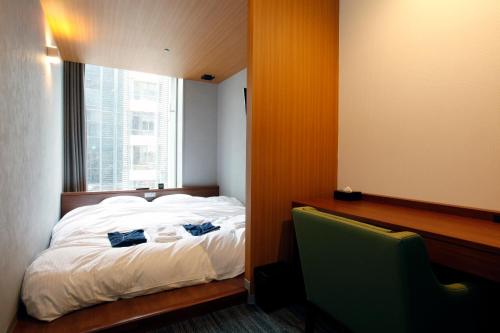 a bedroom with a bed and a desk and a window at Gardens Cabin in Sapporo