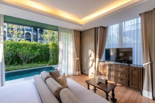 a living room with a large white couch and a tv at Hotel Labaris Khao Yai in Mu Si