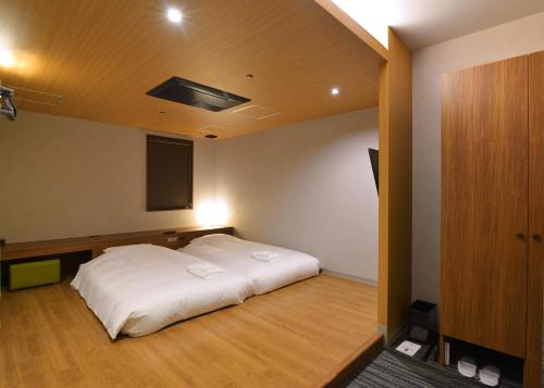 a bedroom with a white bed in a room at Gardens Cabin in Sapporo