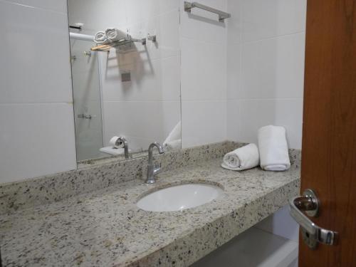 La salle de bains est pourvue d'un lavabo et d'un miroir. dans l'établissement Hotel Padre Cícero, à Juazeiro do Norte