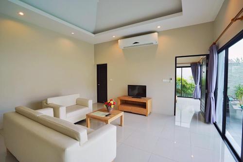 a living room with a couch and a tv at Layantara Villas in Layan Beach