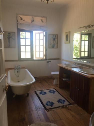 a bathroom with a tub and two sinks and a toilet at The 100 Year Old House in Nanyuki