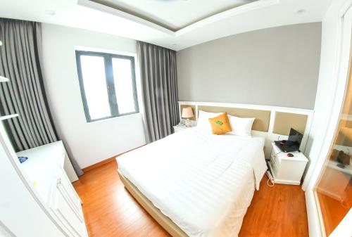 a white bedroom with a bed and a window at GM Hotel and Apartment in Hai Phong