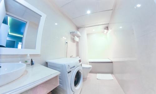a white bathroom with a washing machine in it at GM Hotel and Apartment in Hai Phong