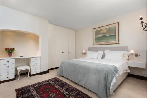 a white bedroom with a bed and a desk at 4 Piet Retief in Stellenbosch