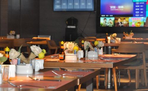 Grand Palace Hotel - Grand Hotel Management Group في قوانغتشو: غرفة طعام مع طاولات وكراسي وتلفزيون