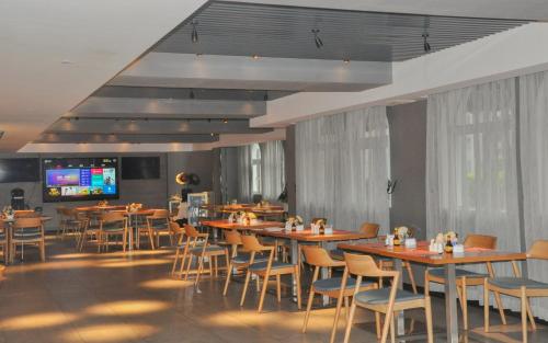 Grand Palace Hotel - Grand Hotel Management Group في قوانغتشو: غرفة طعام مع طاولات وكراسي وتلفزيون