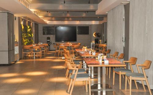 Grand Palace Hotel - Grand Hotel Management Group في قوانغتشو: مطعم مع طاولات وكراسي وتلفزيون بشاشة مسطحة
