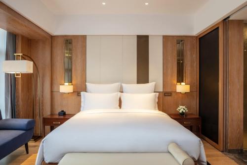 a bedroom with a large white bed and a blue couch at Pullman Changbaishan Resort in Fusong