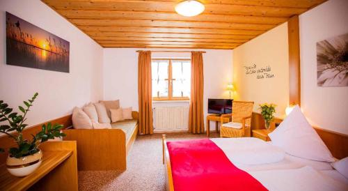 um quarto com uma cama e uma sala de estar com um sofá em Pension Zum Schmidbäcker em Freyung