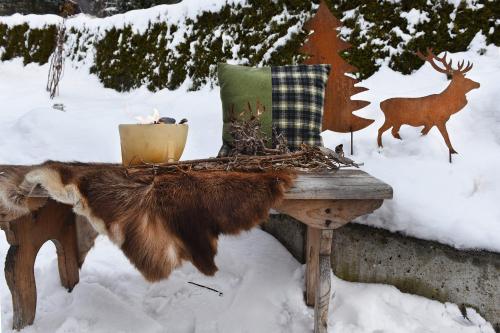 a wooden table in the snow with a deer in the background at Veronikas Chalet in Sankt Gallenkirch