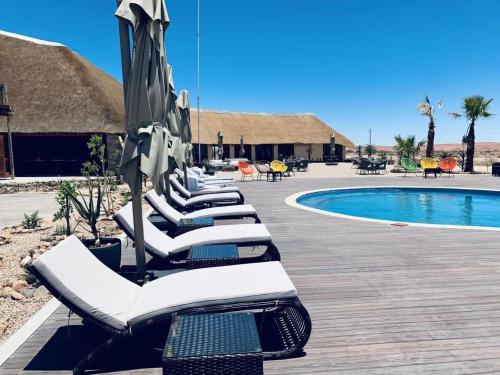 a row of lounge chairs next to a swimming pool at Agama Lodge in Solitaire