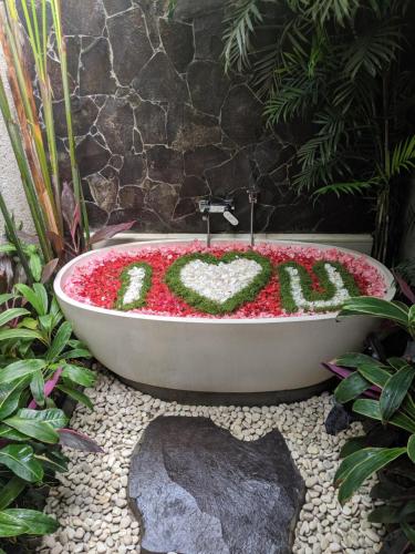 a bath tub with the word love written in flowers at Anusara Luxury Villas in Ubud