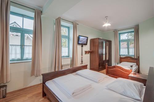 a bedroom with two beds and a tv and windows at Guest House Parma in Maribor