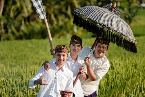 a group of three men holding an umbrella at Cenik Villa Ubud in Ubud
