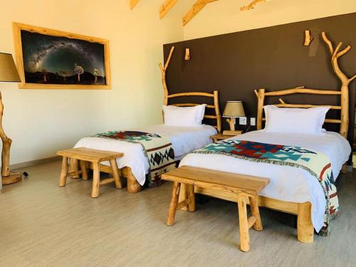 a room with two beds and two benches and a painting at Agama Lodge in Solitaire