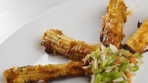 a white plate with corn on the cob and coleslaw at Comfort Hotels in Coimbatore