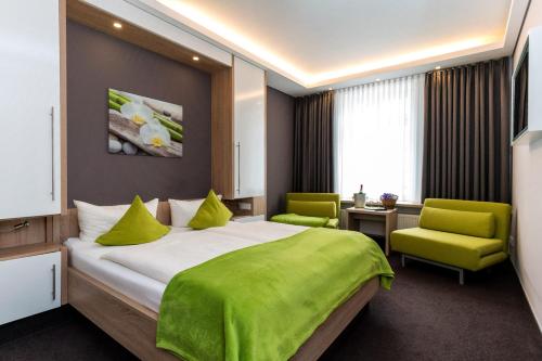 a bedroom with a large bed and two green chairs at Pension Alabama in Warnemünde