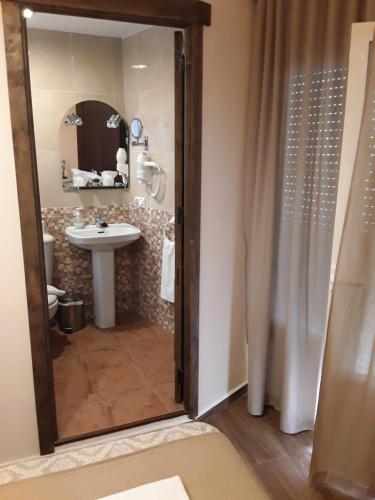y baño con lavabo y ducha con espejo. en Hostal Rocio en Sanlúcar la Mayor