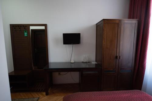 a bedroom with a desk and a cabinet and a television at Pension Arena in Cluj-Napoca