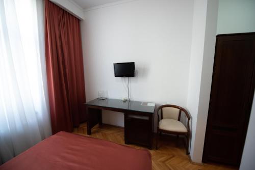 a room with a desk with a tv and a bed at Pension Arena in Cluj-Napoca