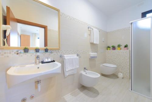 bagno con lavandino, servizi igienici e specchio di Hotel Nuova Medusa Rimini a Rimini