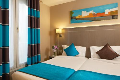 Cette chambre d'hôtel comprend 2 lits avec des touches de bleu. dans l'établissement Beaugrenelle St-Charles Tour Eiffel, à Paris