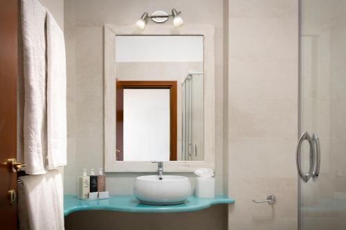 a bathroom with a sink and a mirror at Gabbiano Azzurro Hotel & Suites in Golfo Aranci