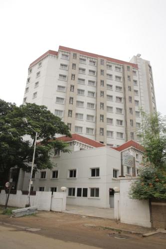 a large white building with a tree in front of it at Rain Drops Hotel in Chennai