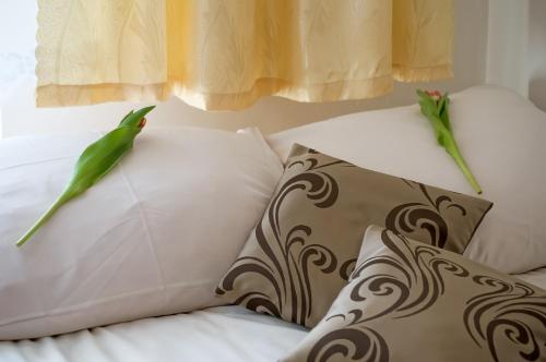 two green birds perched on pillows on a bed at Dom Wypoczynkowy u Niedzielskich in Białka Tatrzanska