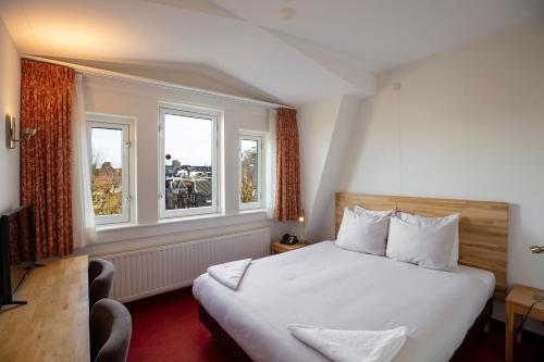 ein Hotelzimmer mit einem Bett und zwei Fenstern in der Unterkunft Amsterdam Wiechmann Hotel in Amsterdam