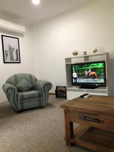 a living room with a tv and a couch and a chair at Beltie Park Homestead in Wangaratta