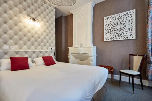 a bedroom with a large white bed with red pillows at Hotel Saint Etienne in Caen