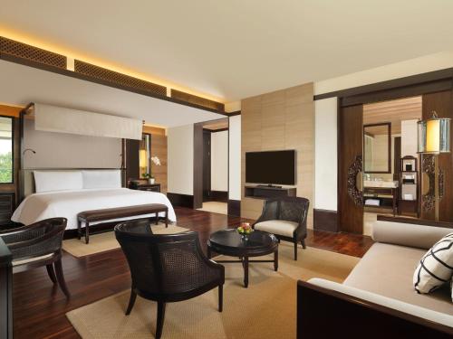 a bedroom with a bed and a living room at The Apurva Kempinski Bali in Nusa Dua