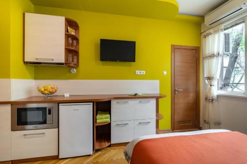 una cocina con paredes amarillas y una cama en una habitación en Studio DOLCE VITA en Varna