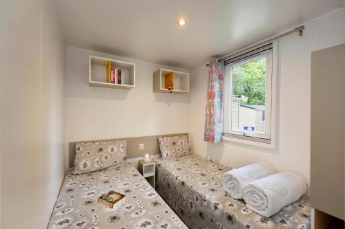 een slaapkamer met 2 bedden en een raam bij Albatross Mobile Homes on Camping Bella Italia in Peschiera del Garda