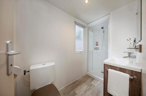 a white bathroom with a toilet and a sink at Albatross Mobile Homes on Camping Bella Italia in Peschiera del Garda