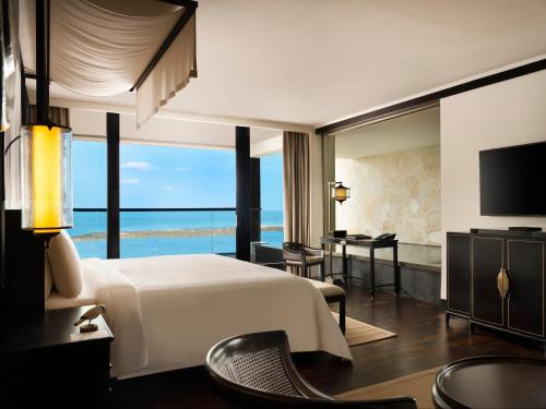 a hotel room with a bed and a view of the ocean at The Apurva Kempinski Bali in Nusa Dua