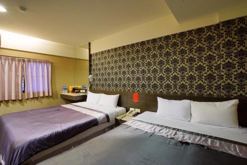 a hotel room with two beds and a wall at Happy Hotel in Kaohsiung