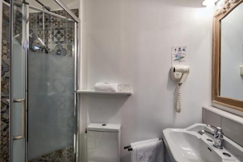 a bathroom with a shower and a toilet and a sink at Hotel Saint Etienne in Caen